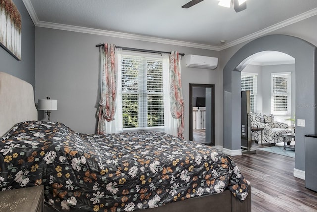 bedroom featuring arched walkways, crown molding, a wall mounted AC, wood finished floors, and baseboards