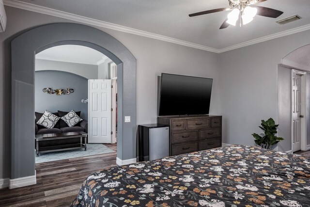 bedroom with arched walkways, dark wood-style flooring, visible vents, baseboards, and crown molding