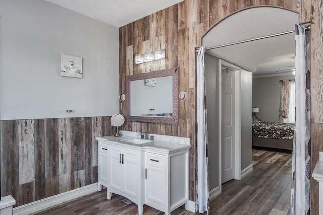 bathroom with ensuite bathroom, wood finished floors, vanity, and wooden walls