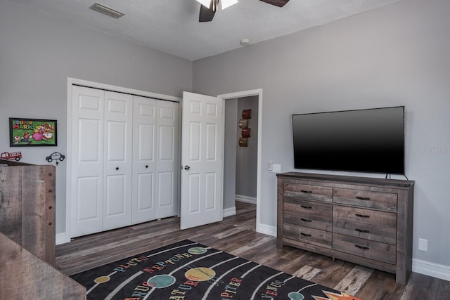 bedroom featuring ceiling fan, dark wood-style flooring, visible vents, baseboards, and a closet