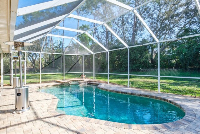 view of pool with a lawn, glass enclosure, fence, a patio area, and a pool with connected hot tub