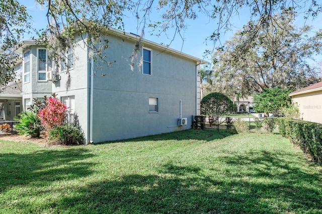 view of home's exterior featuring fence, a lawn, and stucco siding