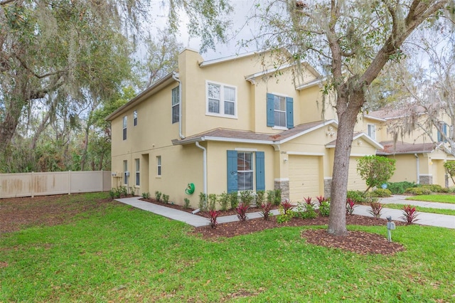 view of front of home featuring a garage, fence, driveway, stucco siding, and a front yard