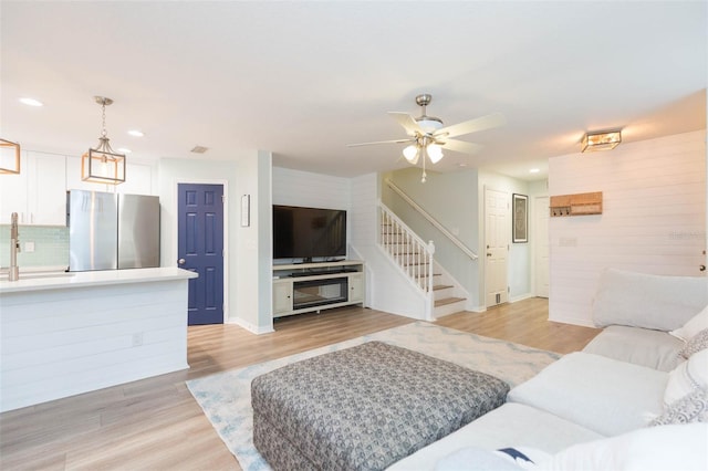 living room featuring light wood-style floors, stairway, and recessed lighting