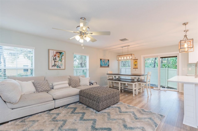 living room featuring plenty of natural light, wood finished floors, visible vents, and a ceiling fan