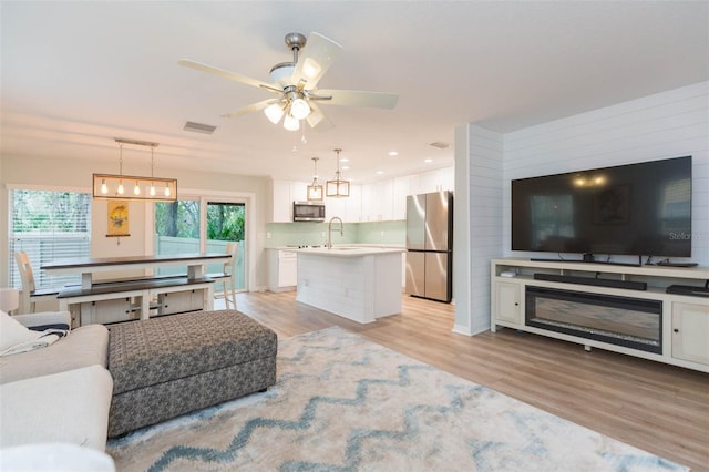 living room with light wood finished floors, ceiling fan, visible vents, and recessed lighting