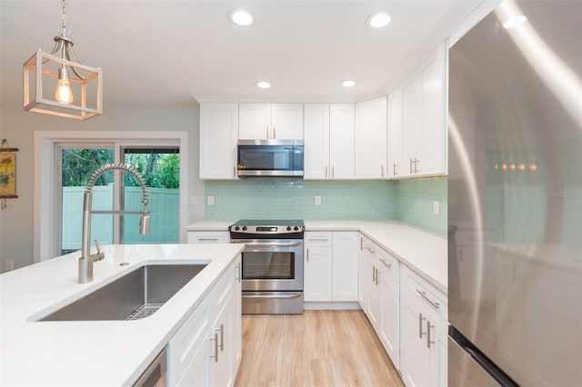 kitchen featuring light countertops, backsplash, appliances with stainless steel finishes, light wood-style floors, and a sink