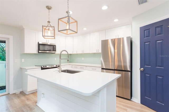 kitchen with decorative backsplash, stainless steel appliances, light countertops, light wood-type flooring, and a sink