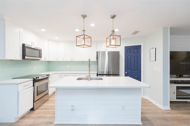 kitchen featuring light wood finished floors, stainless steel appliances, decorative backsplash, and light countertops