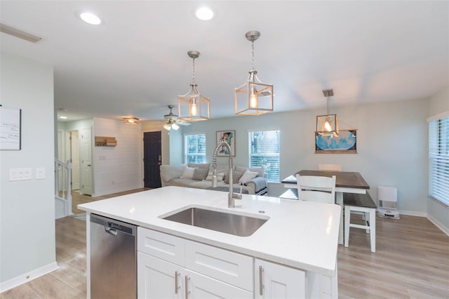 kitchen featuring white cabinets, open floor plan, decorative light fixtures, light wood-style floors, and stainless steel dishwasher