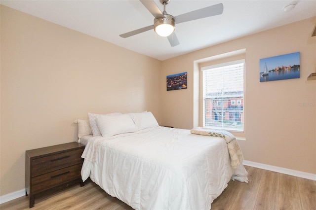 bedroom with ceiling fan, light wood finished floors, and baseboards