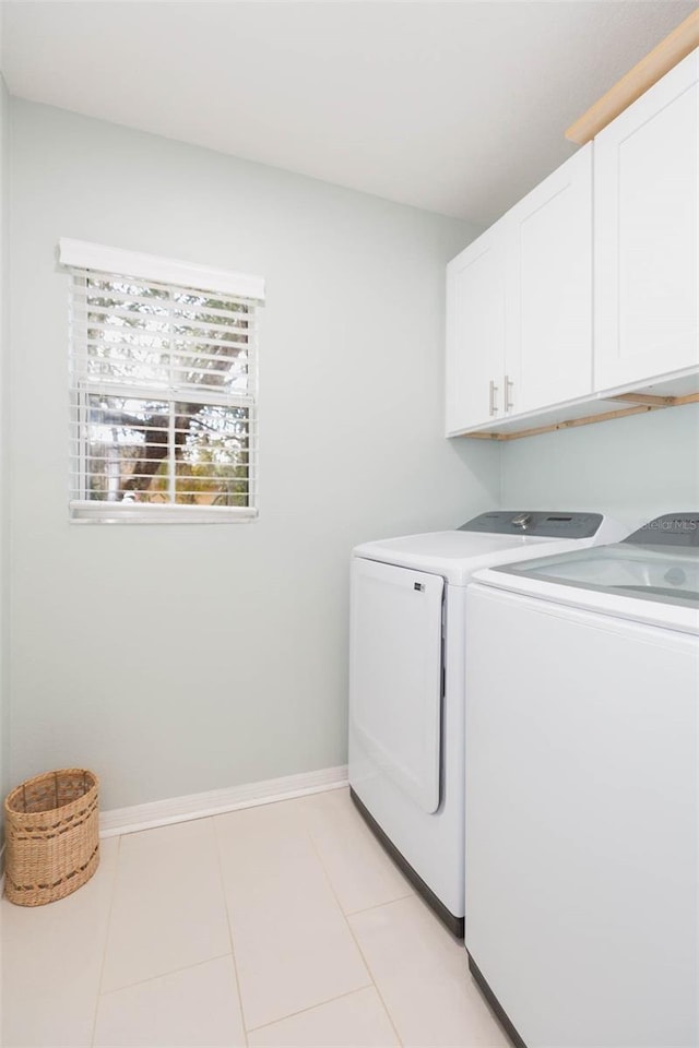 laundry area featuring cabinet space, washing machine and dryer, baseboards, and light tile patterned flooring