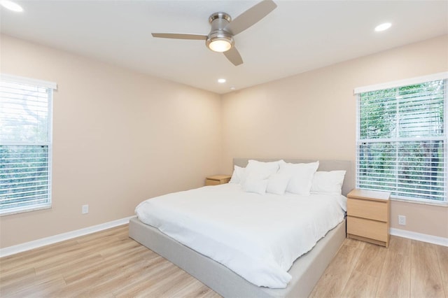 bedroom with light wood-style flooring, multiple windows, and baseboards