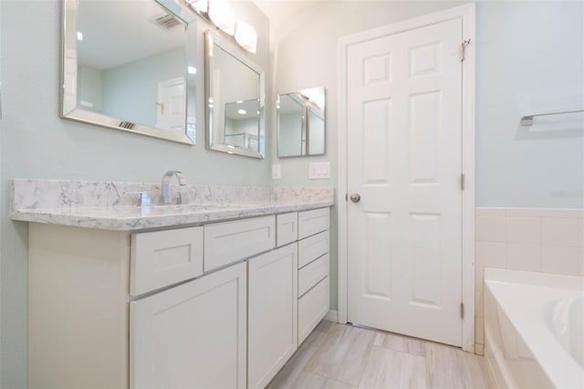 bathroom featuring a garden tub, visible vents, and vanity