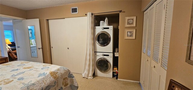 bedroom with visible vents, stacked washer / dryer, carpet, a textured ceiling, and two closets