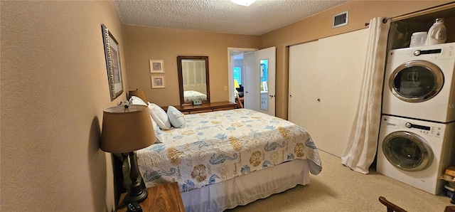 bedroom with carpet floors, a closet, visible vents, a textured ceiling, and stacked washing maching and dryer