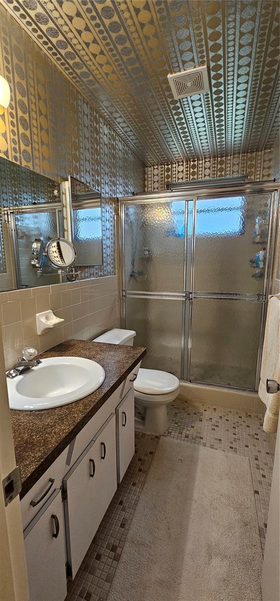 bathroom featuring backsplash, toilet, a shower stall, and vanity