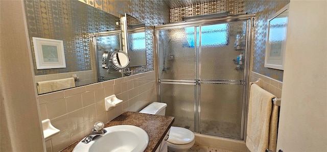 bathroom featuring a stall shower, tile walls, toilet, and vanity