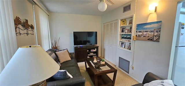 carpeted living room with a textured ceiling, ceiling fan, and visible vents