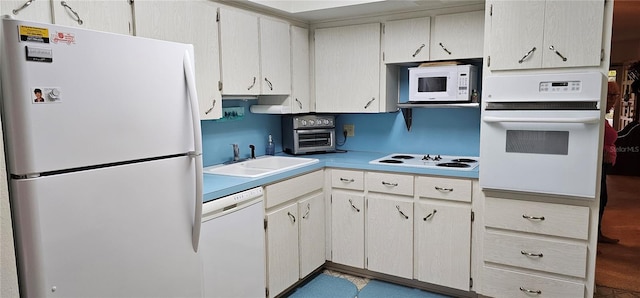 kitchen with white appliances, a toaster, light countertops, and a sink