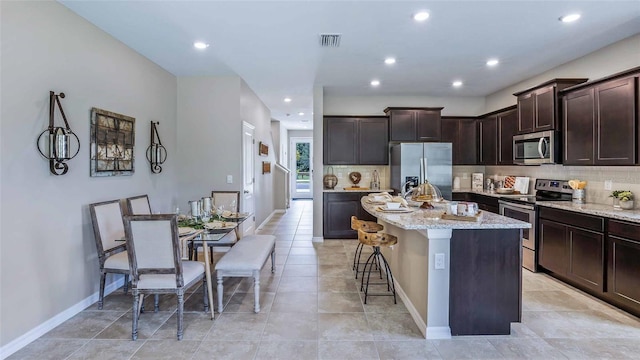 kitchen featuring visible vents, a kitchen island, appliances with stainless steel finishes, and dark brown cabinets