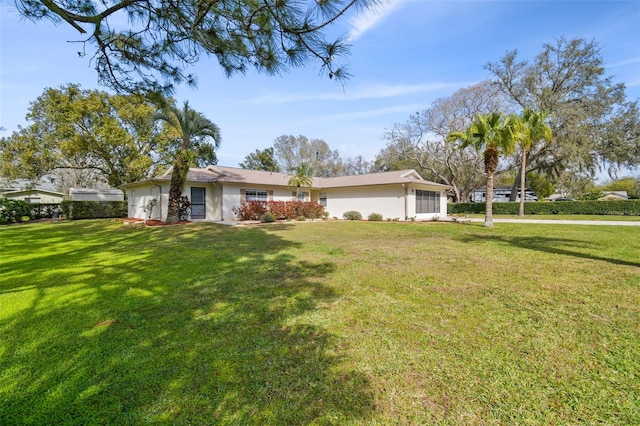 ranch-style house featuring a front lawn and stucco siding