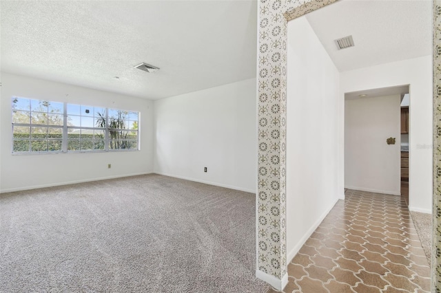 spare room with carpet, baseboards, visible vents, and a textured ceiling