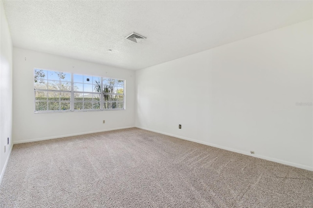 carpeted spare room with a textured ceiling, visible vents, and baseboards