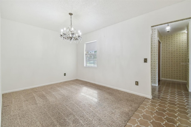 carpeted spare room with wallpapered walls, a textured ceiling, baseboards, and an inviting chandelier