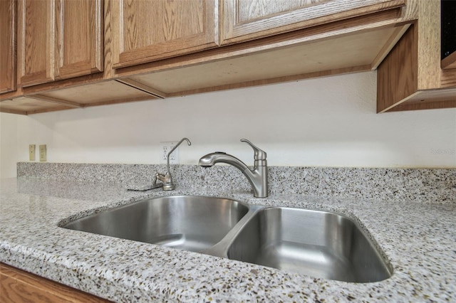 room details featuring light stone counters and a sink