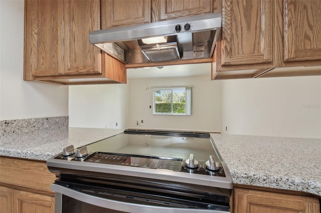 kitchen with stainless steel electric stove, brown cabinetry, and exhaust hood