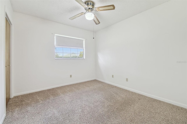 carpeted spare room with ceiling fan, baseboards, and a textured ceiling