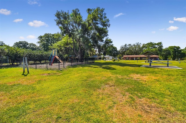 view of property's community featuring playground community, fence, and a lawn