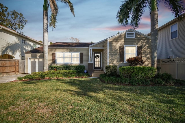 view of front of house featuring a garage, concrete driveway, a front lawn, and fence