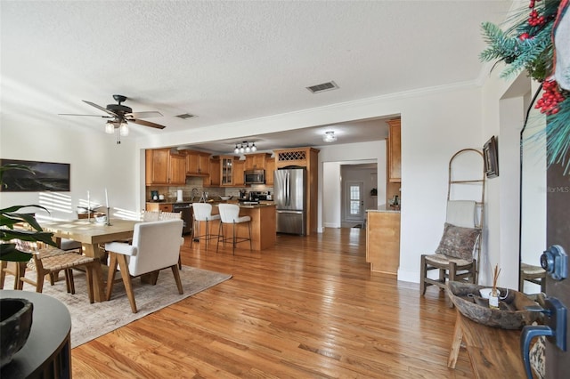 dining room featuring visible vents, light wood-style flooring, and a textured ceiling