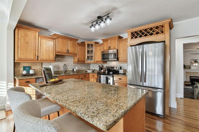 kitchen featuring stainless steel appliances, light stone countertops, glass insert cabinets, and a center island