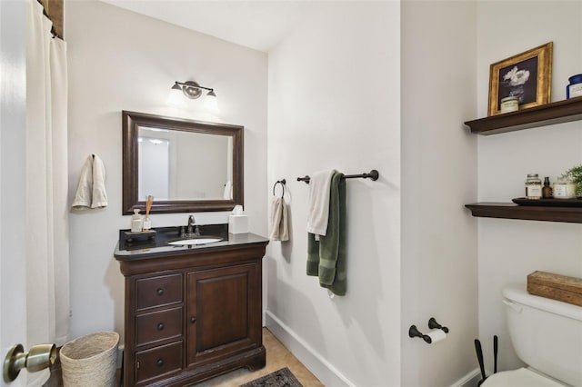 full bath featuring toilet, vanity, and baseboards