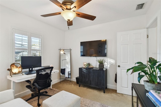 office featuring light colored carpet, visible vents, ceiling fan, and baseboards