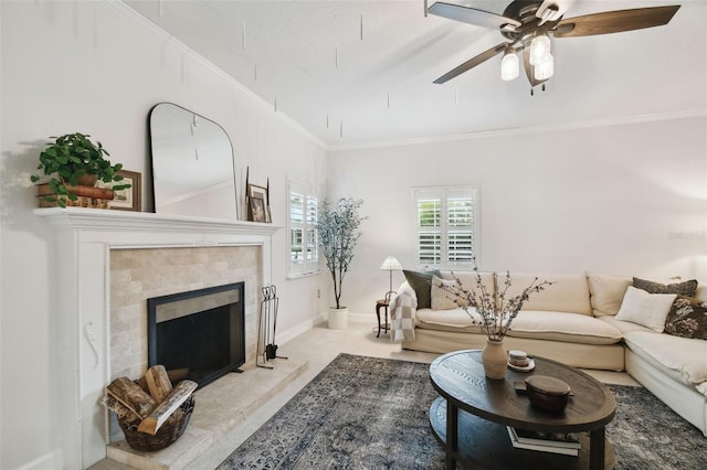 carpeted living area with ornamental molding, baseboards, a tiled fireplace, and a ceiling fan