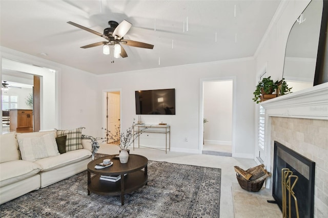 living room featuring light tile patterned floors, baseboards, ceiling fan, ornamental molding, and a fireplace