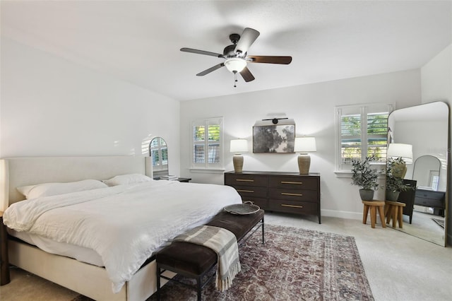 bedroom featuring baseboards, ceiling fan, multiple windows, and light colored carpet