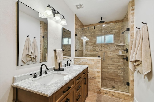 full bathroom with double vanity, a shower stall, visible vents, and a sink