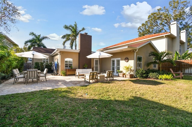 rear view of property featuring a chimney, fence, and stucco siding