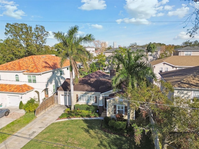 view of front facade with concrete driveway, a front yard, fence, and a residential view