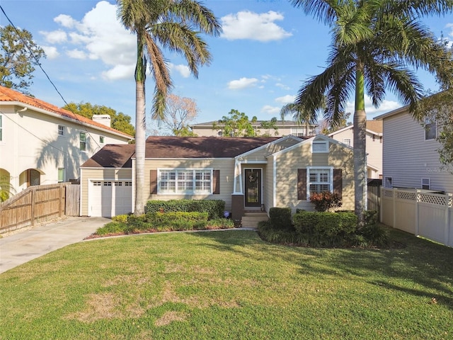 view of front of house with driveway, an attached garage, fence, and a front yard