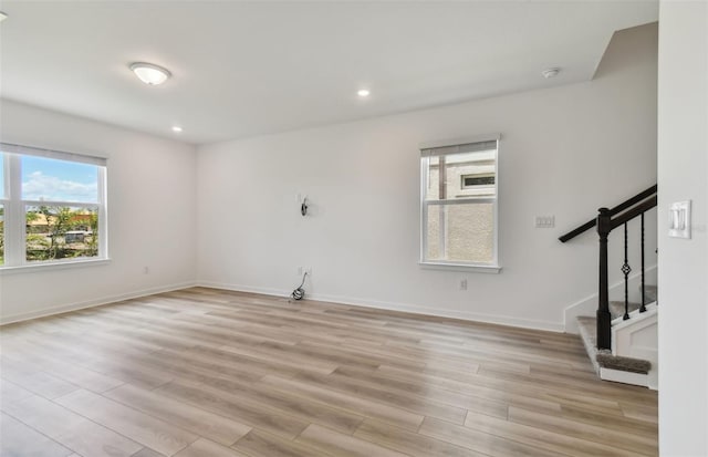 unfurnished room featuring stairway, recessed lighting, light wood-style flooring, and baseboards