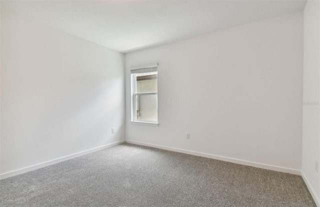 carpeted spare room featuring baseboards