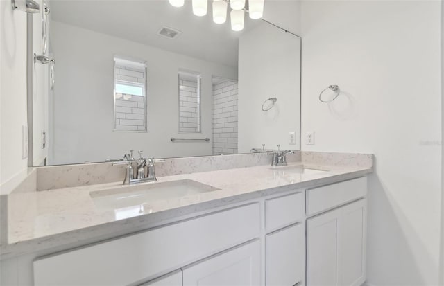 bathroom with double vanity, a sink, and visible vents