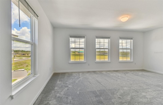 empty room with a wealth of natural light, carpet flooring, and baseboards