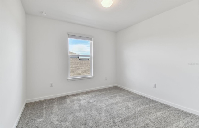 carpeted spare room featuring baseboards